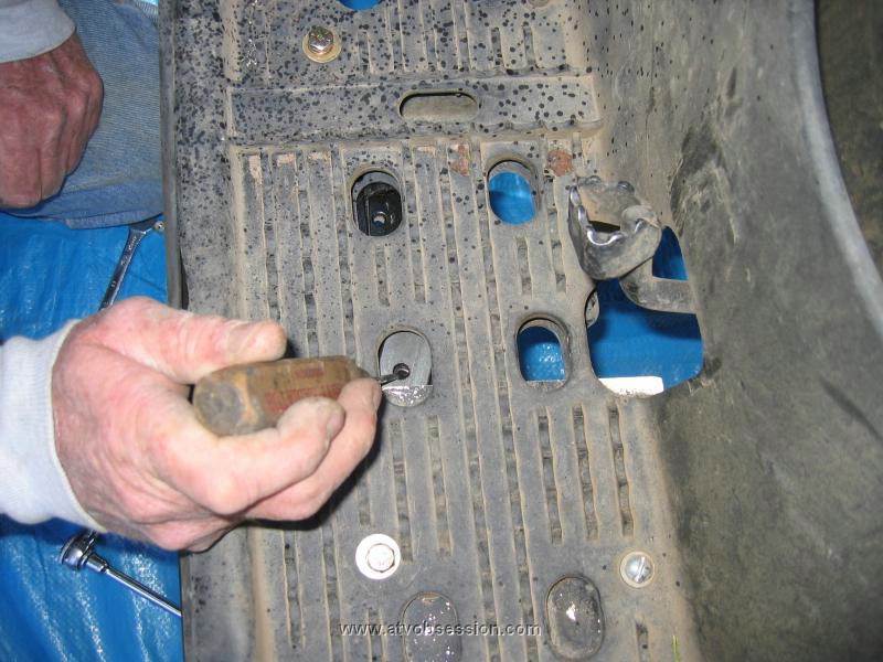 08. Step 6. Use a small screw driver to help guide the plate into position between the metal brace and the plastic footwell..jpg